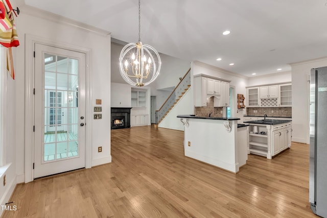 85 Christenbury Ln, Clayton, NC 27527 - kitchen featuring a kitchen breakfast bar, dark countertops, open shelves, a warm lit fireplace, and an inviting chandelier
