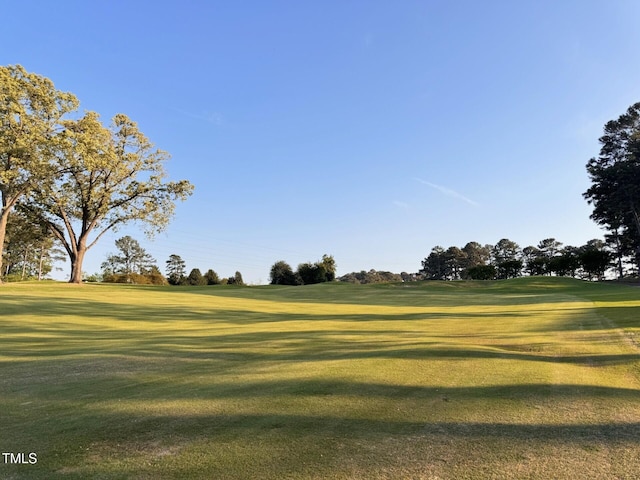 surrounding community with golf course view and a lawn