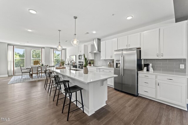 1245 S Blount St Unit 201, Raleigh, NC 27601 - kitchen with wall chimney exhaust hood, light countertops, white cabinetry, a center island with sink, and stainless steel appliances