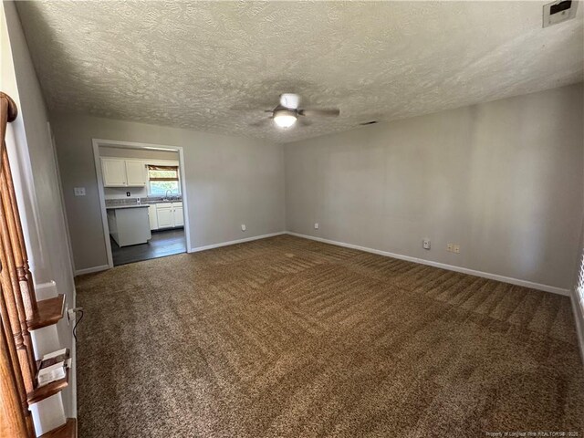 5870 Mcdonald Rd, Parkton, NC 28371 - empty room featuring baseboards, a ceiling fan, dark carpet, and a textured ceiling