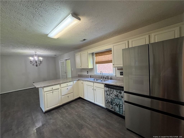 5870 Mcdonald Rd, Parkton, NC 28371 - kitchen featuring freestanding refrigerator, a peninsula, a textured ceiling, a sink, and a notable chandelier