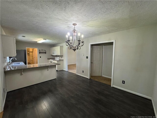 5870 Mcdonald Rd, Parkton, NC 28371 - kitchen featuring white cabinets, an inviting chandelier, a sink, a peninsula, and dark wood-style floors