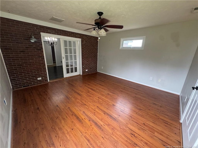 5870 Mcdonald Rd, Parkton, NC 28371 - unfurnished room featuring brick wall, wood finished floors, and ceiling fan with notable chandelier