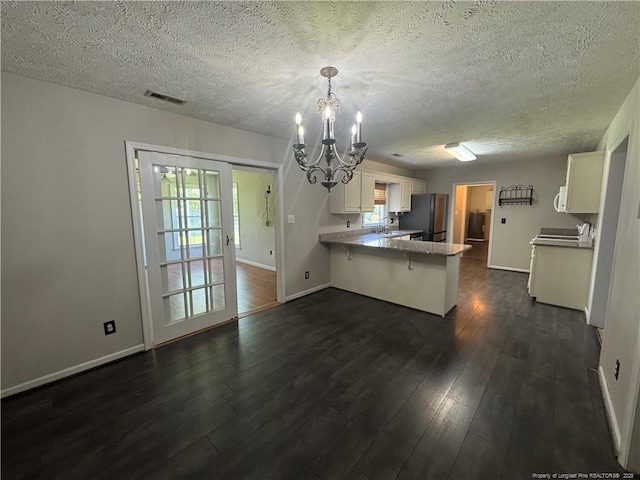 5870 Mcdonald Rd, Parkton, NC 28371 - kitchen with visible vents, freestanding refrigerator, an inviting chandelier, a peninsula, and dark wood finished floors