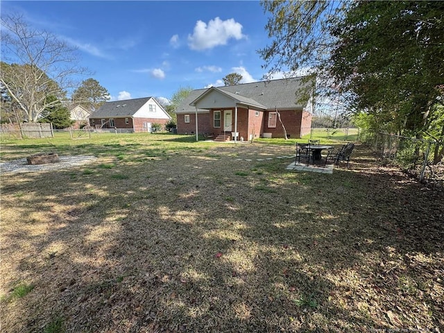 5870 Mcdonald Rd, Parkton, NC 28371 - rear view of property featuring a patio, a fenced backyard, brick siding, entry steps, and a lawn