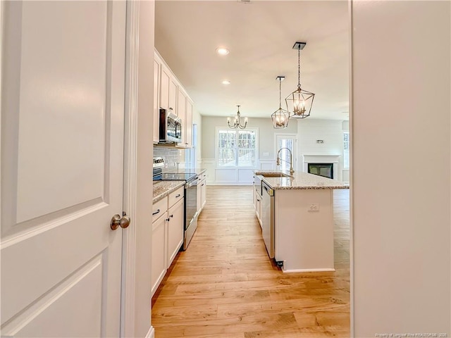 1312 Cory Cir, Fayetteville, NC 28312 - kitchen featuring light wood-type flooring, white cabinets, a chandelier, a sink, and appliances with stainless steel finishes