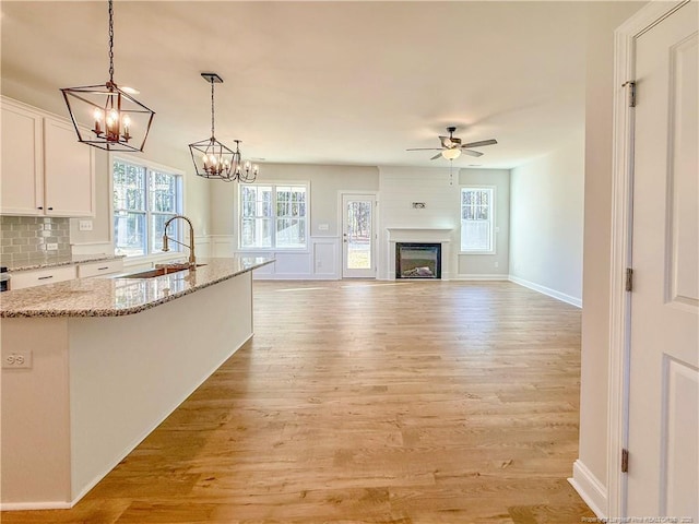 1312 Cory Cir, Fayetteville, NC 28312 - kitchen with light stone counters, a sink, light wood finished floors, white cabinetry, and a center island with sink