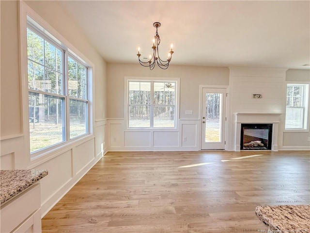 1312 Cory Cir, Fayetteville, NC 28312 - unfurnished dining area with an inviting chandelier, a fireplace, light wood-style floors, a decorative wall, and a wainscoted wall
