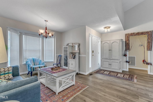 9512 Anson Grove Ln, Raleigh, NC 27615 - entrance foyer with a notable chandelier, wood finished floors, a textured ceiling, baseboards, and visible vents