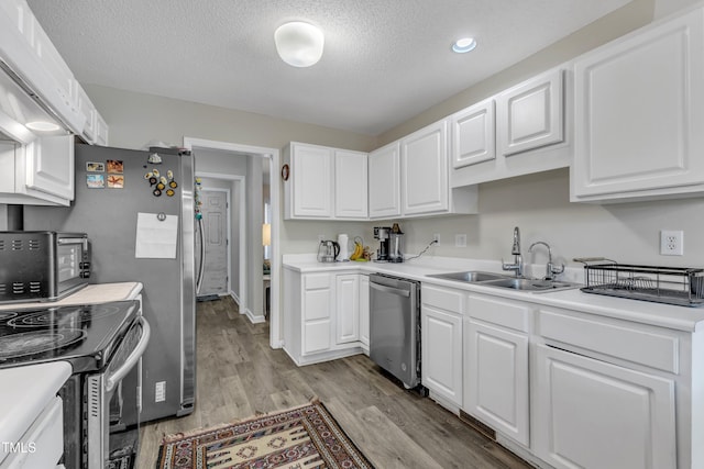 9512 Anson Grove Ln, Raleigh, NC 27615 - kitchen with light countertops, a sink, appliances with stainless steel finishes, light wood-style flooring, and white cabinets
