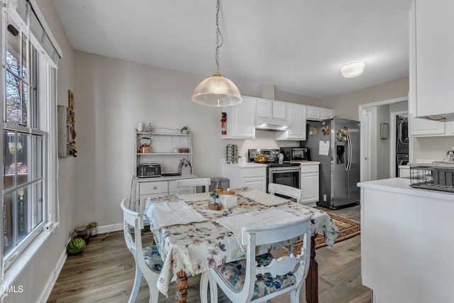 9512 Anson Grove Ln, Raleigh, NC 27615 - dining room featuring stacked washer / dryer, baseboards, and light wood-type flooring