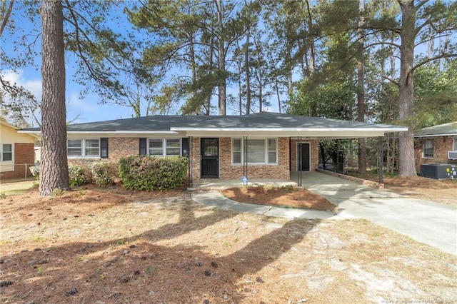 ranch-style house featuring central AC unit, brick siding, a carport, and concrete driveway