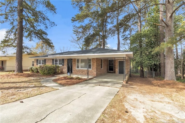 ranch-style house featuring brick siding, fence, an attached carport, and driveway
