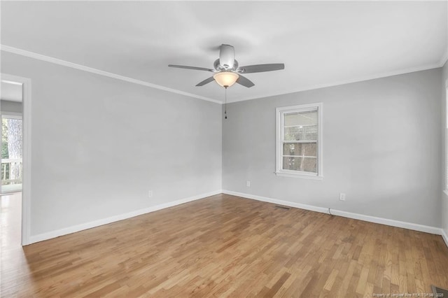 empty room featuring wood finished floors, baseboards, crown molding, and ceiling fan