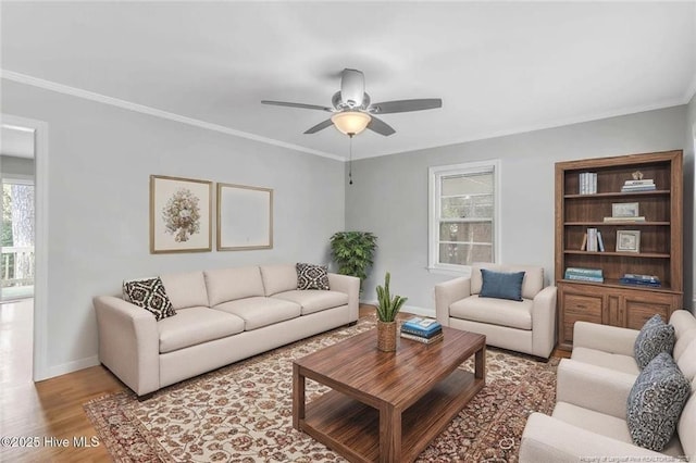 living room with crown molding, light wood-style flooring, a ceiling fan, and baseboards