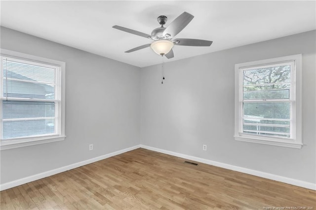 spare room featuring light wood-style floors, baseboards, a ceiling fan, and visible vents
