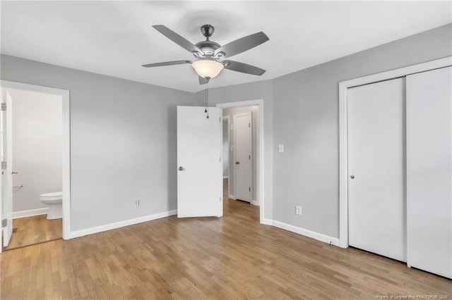 unfurnished bedroom featuring light wood-type flooring, a closet, baseboards, and connected bathroom