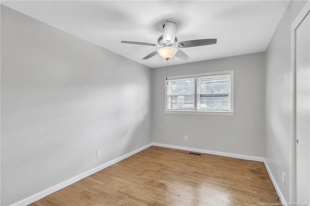 empty room with ceiling fan, visible vents, baseboards, and wood finished floors