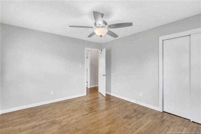 unfurnished bedroom featuring a closet, baseboards, ceiling fan, and wood finished floors