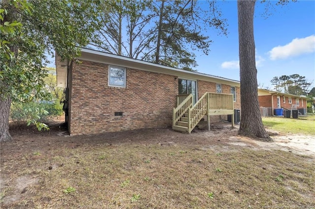 back of property with brick siding, cooling unit, and crawl space