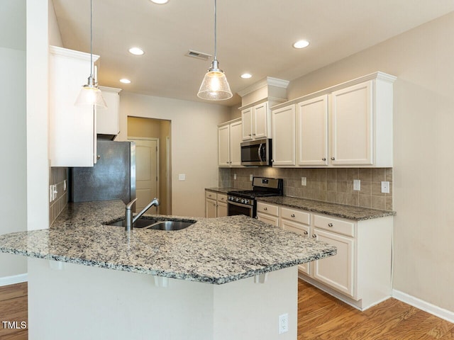 112 Churment Ct, Durham, NC 27703 - kitchen featuring stainless steel appliances, a peninsula, light wood finished floors, recessed lighting, and backsplash