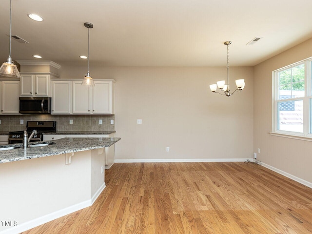 112 Churment Ct, Durham, NC 27703 - kitchen with stainless steel appliances, light wood-style flooring, decorative backsplash, a chandelier, and recessed lighting