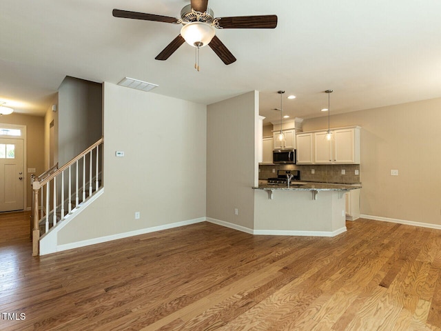 112 Churment Ct, Durham, NC 27703 - kitchen featuring appliances with stainless steel finishes, a kitchen breakfast bar, wood finished floors, stone countertops, and recessed lighting