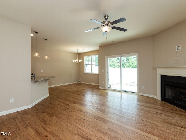 112 Churment Ct, Durham, NC 27703 - unfurnished living room featuring a fireplace, ceiling fan, a chandelier, and wood finished floors
