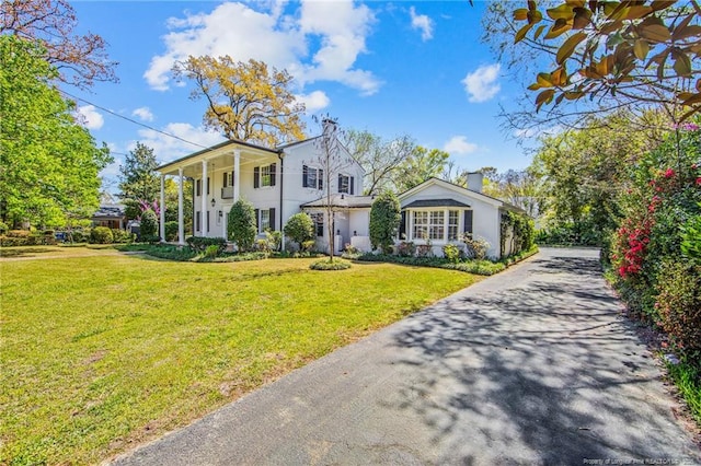neoclassical home featuring stucco siding, aphalt driveway, and a front lawn