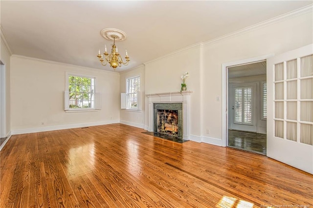 unfurnished living room featuring baseboards, a high end fireplace, a chandelier, crown molding, and wood finished floors