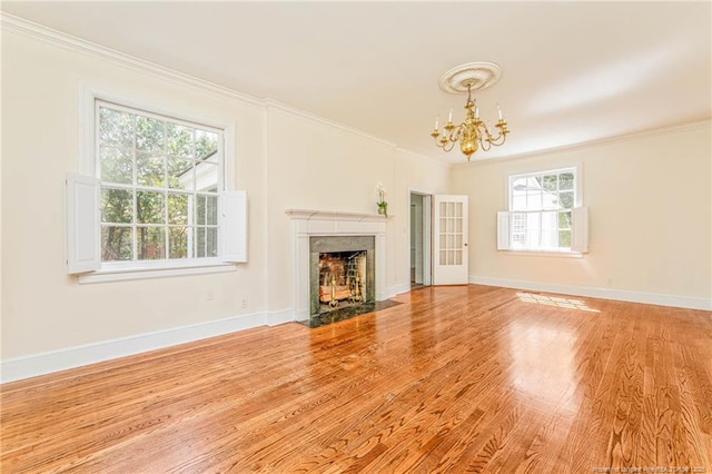 unfurnished living room with baseboards, an inviting chandelier, crown molding, wood finished floors, and a fireplace