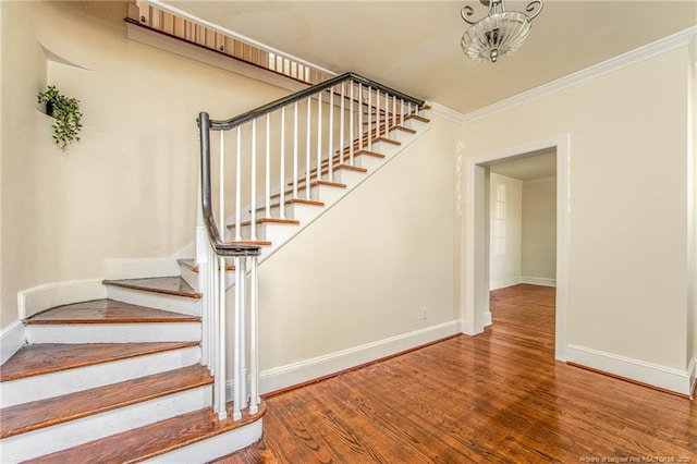 stairs with wood finished floors, baseboards, and ornamental molding