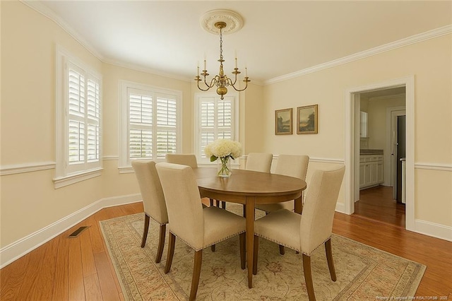 dining room featuring a chandelier, wood finished floors, baseboards, and ornamental molding
