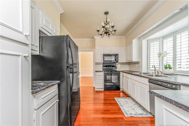 kitchen featuring a sink, wood finished floors, black appliances, crown molding, and a chandelier