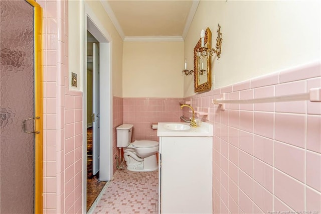 bathroom featuring tile walls, toilet, vanity, crown molding, and a wainscoted wall