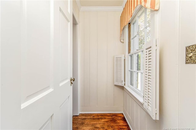 doorway with ornamental molding, a decorative wall, and dark wood-type flooring