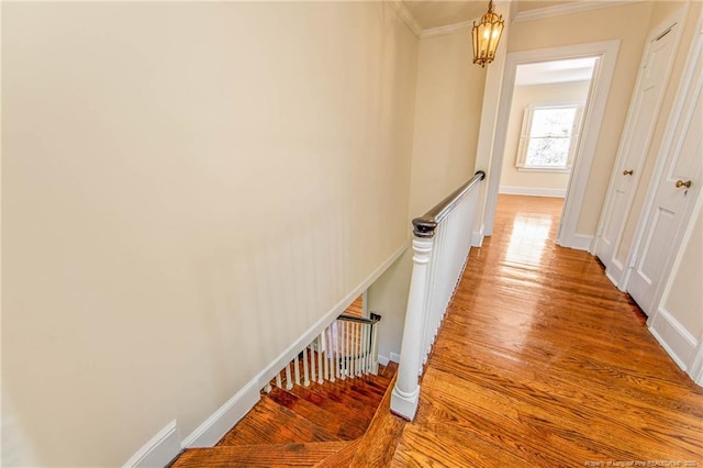 corridor with baseboards, an upstairs landing, crown molding, and wood finished floors