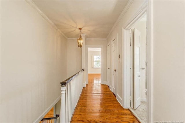 corridor with an inviting chandelier, crown molding, an upstairs landing, and wood finished floors