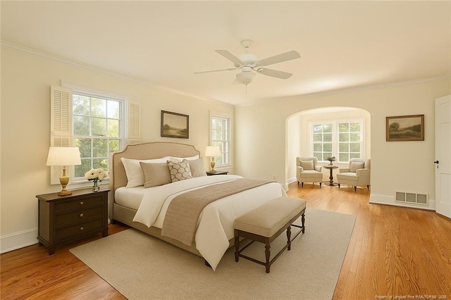 bedroom featuring arched walkways, ornamental molding, and visible vents
