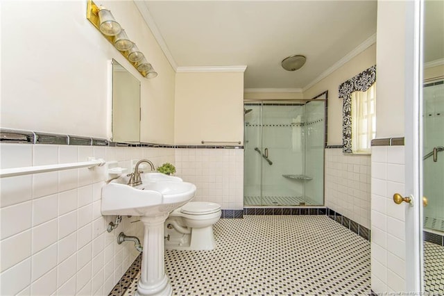 bathroom featuring toilet, tile walls, crown molding, wainscoting, and a shower stall