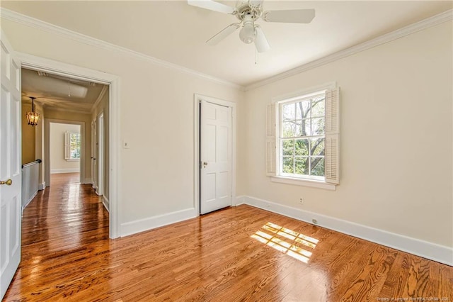unfurnished bedroom with baseboards, multiple windows, ornamental molding, and attic access