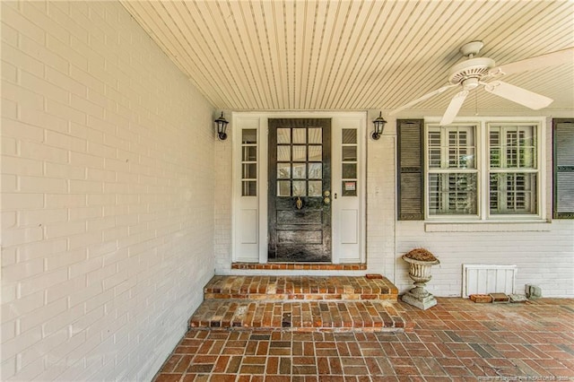 entrance to property with a ceiling fan and brick siding