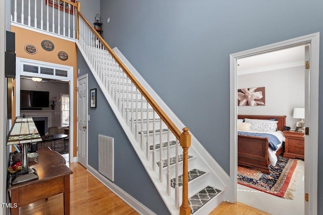 15 Longwood Dr, Youngsville, NC 27596 - staircase with visible vents, baseboards, a fireplace, wood finished floors, and a high ceiling