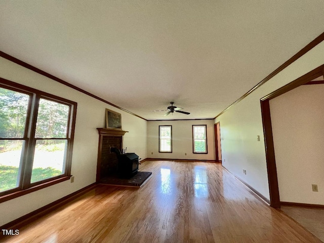 1401 Roy Averette Dr, Raleigh, NC 27603 - unfurnished living room featuring crown molding, light wood finished floors, ceiling fan, and a wood stove