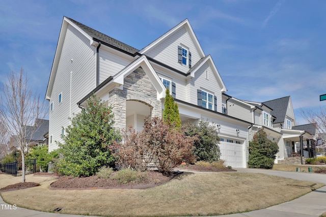view of front of property with an attached garage, fence, stone siding, and concrete driveway