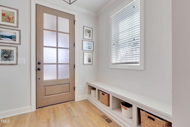 mudroom with light wood-style floors, baseboards, crown molding, and visible vents
