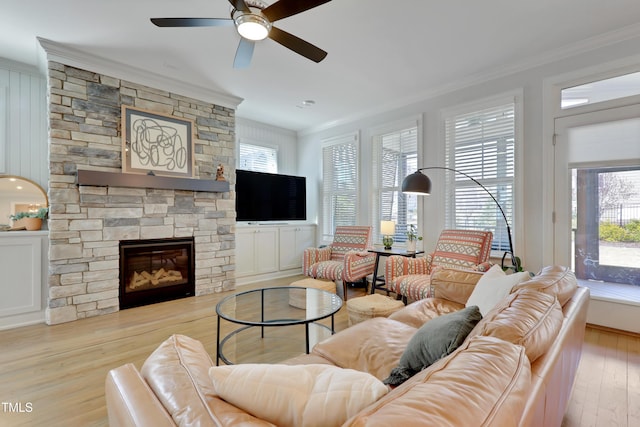 living area featuring plenty of natural light, ornamental molding, a fireplace, and wood finished floors