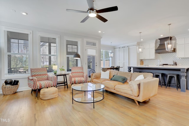 living room with a ceiling fan, baseboards, recessed lighting, and light wood-style flooring