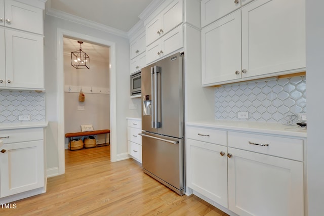kitchen with ornamental molding, light wood-style floors, light countertops, white cabinets, and appliances with stainless steel finishes