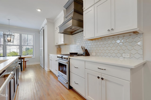 kitchen featuring an inviting chandelier, custom exhaust hood, light wood-type flooring, tasteful backsplash, and appliances with stainless steel finishes